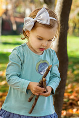 Adorable little girl is playing on an autumn background