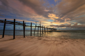 Fototapeta premium Długi drewniany most na plaży o zachodzie słońca