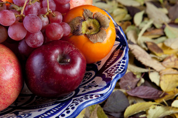 Naklejka na ściany i meble Still life with autumn fruits over dry leaves surface