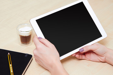 Girl holding a tablet pc at work place with a coffee