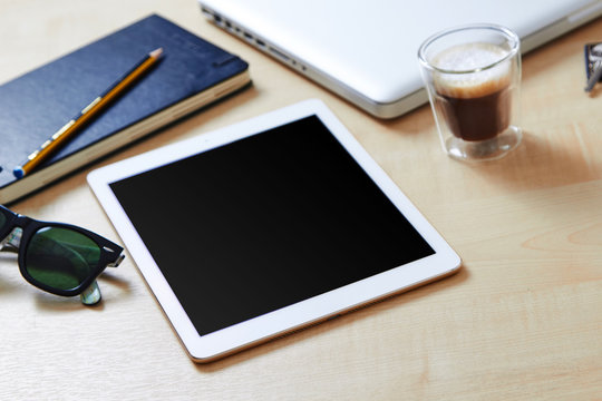 Technology gadgets on a wooden desk, blank screen