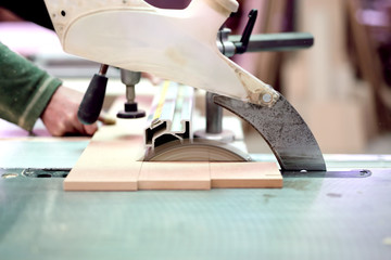 wood factory worker cutting wood boards with sliding saw