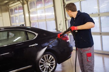 Obraz na płótnie Canvas Man worker washing luxury car on a car wash