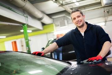 Cheerful worker wiping car on a car wash