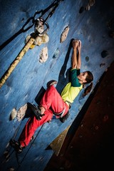 Young woman practicing rock-climbing on a rock wall indoors