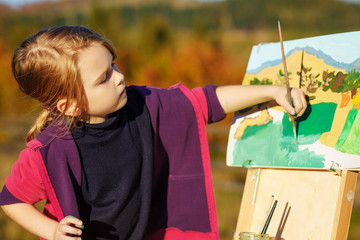Little painter at work near waterfall