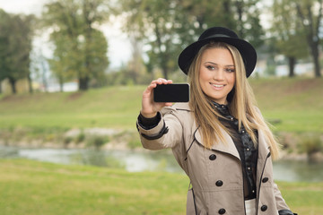 Young woman taking a selfie in park in autumn. No retouch