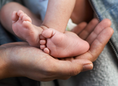 Mom keeps  miniature newborn leg in hand