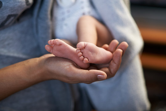 Mom keeps  miniature newborn feet in hands