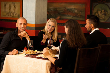 Young people eat sea food dinner at restaurant and drink wine