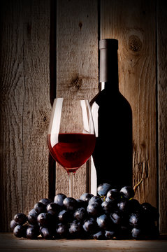 Glass with red wine bottle and grapes