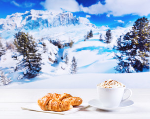 cup of cappuccino with whipped cream and croissants