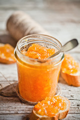 orange jam in a glass jar and bread