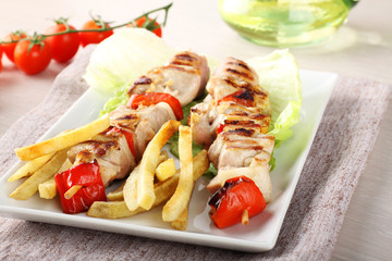 Skewers of mixed meat with french fries and vegetables
