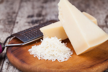grated parmesan cheese and metal grater on wooden board © Gresei