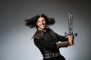 Angry knight with sword against dark background