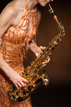 Sexual young woman posing with saxophone at studio
