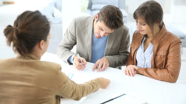 Young couple in real estate agency signing property agreement