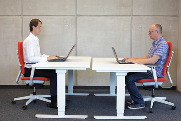 two men coworking in correct sitting posture on chairs in office