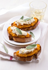 Bruschetta with pumpkin puree, ricotta and sage on a white plate