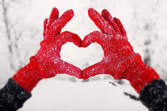 Woman's hands in red gloves on winter natural background
