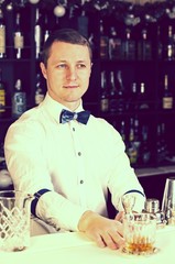 young man working as a bartender in a nightclub bar