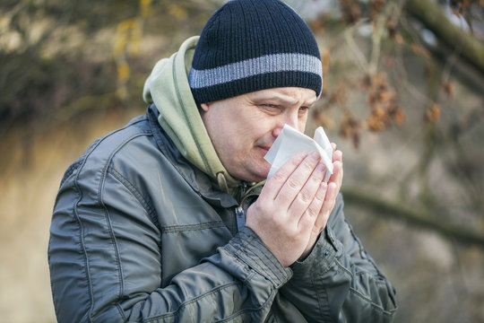 Man with napkin near nose at outdoors on the bench