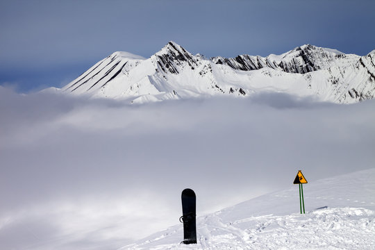 Warning sing, snowboard on off-piste and mountains in fog