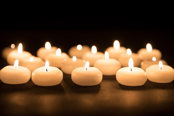 Several white candles with selective focus at a black background