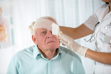 Nurse bandaging older man eyes