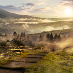 Fototapety  schodzi do wioski w mglistych górach o zachodzie słońca