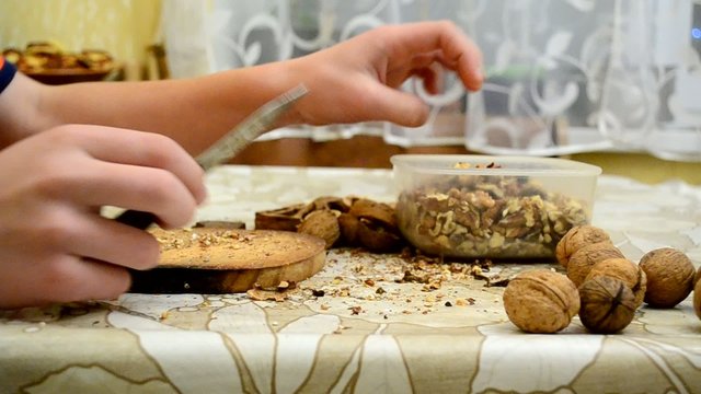 Teenager skilfully cracking walnuts with a knife
