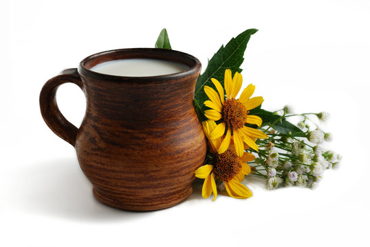 Milk in brown ceramic bowl and summer flowers