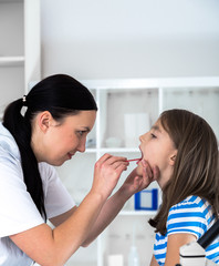 Doctor check throat of little girl