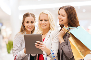 happy young women with tablet pc and shopping bags