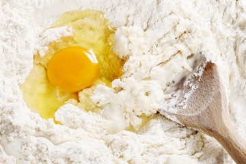 Breaking eggs into flour to make bread dough