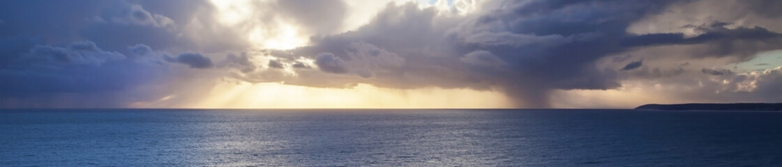 Obraz premium Amazing skyscape panorama with sunset behind clouds over sea.