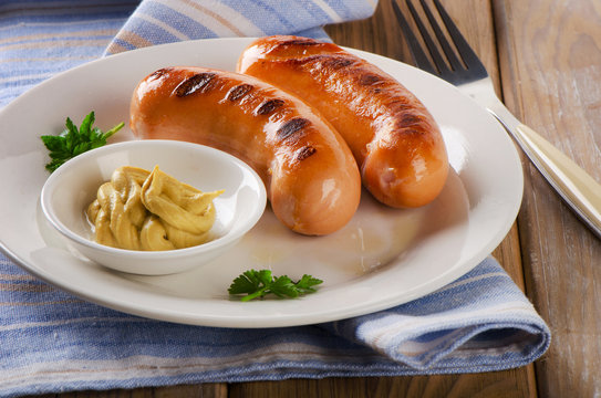Two grilled sausages with mustard