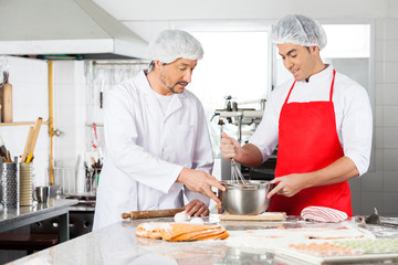 Chefs Discussing While Preparing Ravioli Pasta In Kitchen