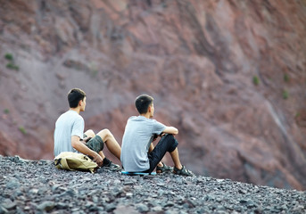 Two young men sitting on rocky cliff