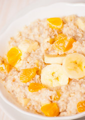 Bowl of oats porridge with banana and tangerine