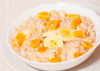 Bowl of oats porridge with banana and tangerine