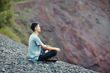 Fototapeta na wymiar Young man relaxing on rocky cliff