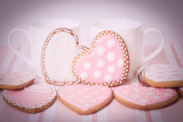 two cups and heart cookies on pink