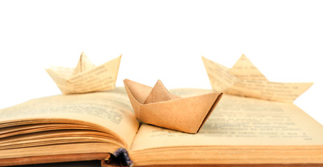 Origami boats on old book, on white background