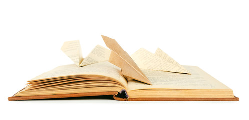 Origami airplanes on old book, on white background