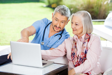 Male Caretaker Assisting Senior Woman In Using Laptop