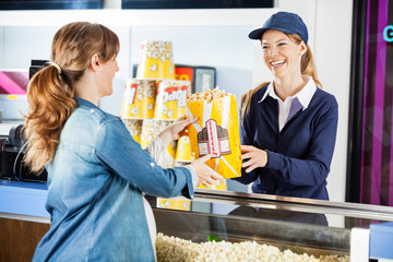 Happy Seller Giving Popcorn To Pregnant Woman At Concession Stan © Tyler Olson