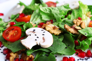 Fresh salad with greens, garnet and spices close-up background