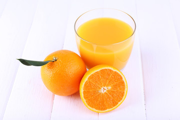 Glass of fresh orange juice on white wooden table